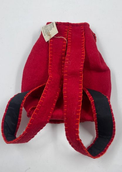 Funky Yak handmade red wool felt finger puppet backpack — back view with swing tag showing the padded navy-lined straps and orange blanket-stitch construction detail