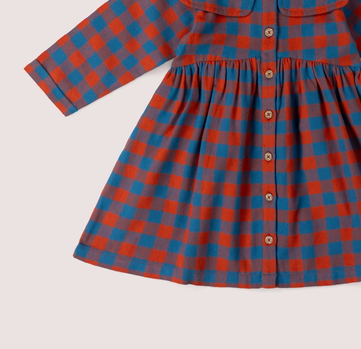 Little Green Rascals burnt ochre and teal blue check sailor dress — close-up detail of the full-length button opening showing the natural coconut shell buttons and the gathered waist seam where the fitted bodice meets the full skirt