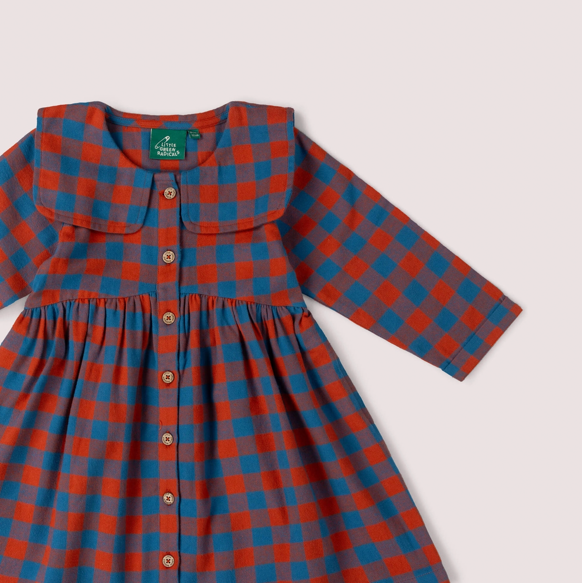 Little Green Rascals burnt ochre and teal blue check sailor dress — close-up detail of the wide flat sailor collar, Little Green Rascals teal woven label at the back neck, and the top natural coconut shell buttons of the full-length button opening