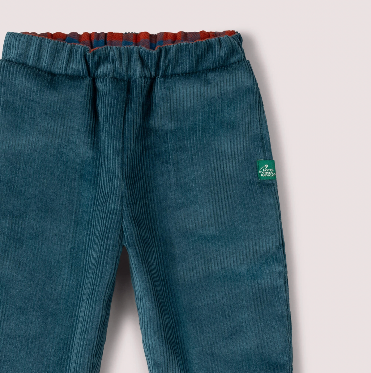 Little Green Rascals Calm Sea Check reversible pull-on trousers — close-up of the corduroy side waistband showing the rich teal wide-wale corduroy, elasticated waist with burnt ochre and teal blue check fabric visible at the top, and Little Green Rascals green woven label badge on the right hip