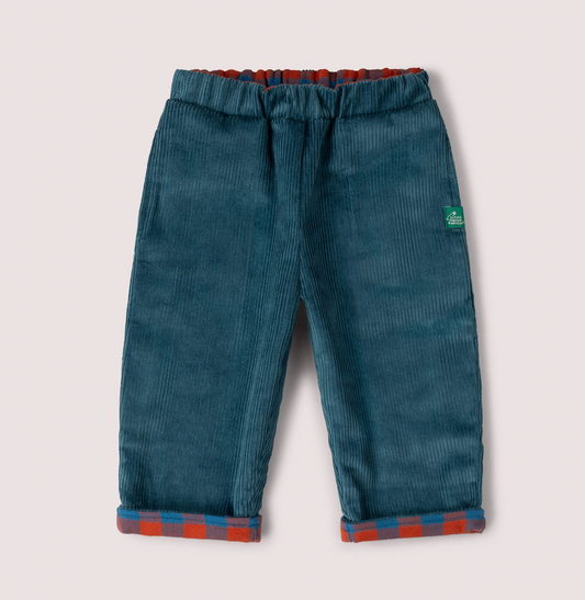 Little Green Rascals Calm Sea Check reversible pull-on trousers — corduroy side showing rich teal wide-wale corduroy with burnt ochre and teal blue check fabric peeking at the elasticated waistband and turn-up cuffs; Little Green Rascals green woven label badge on the right hip; roomy relaxed fit