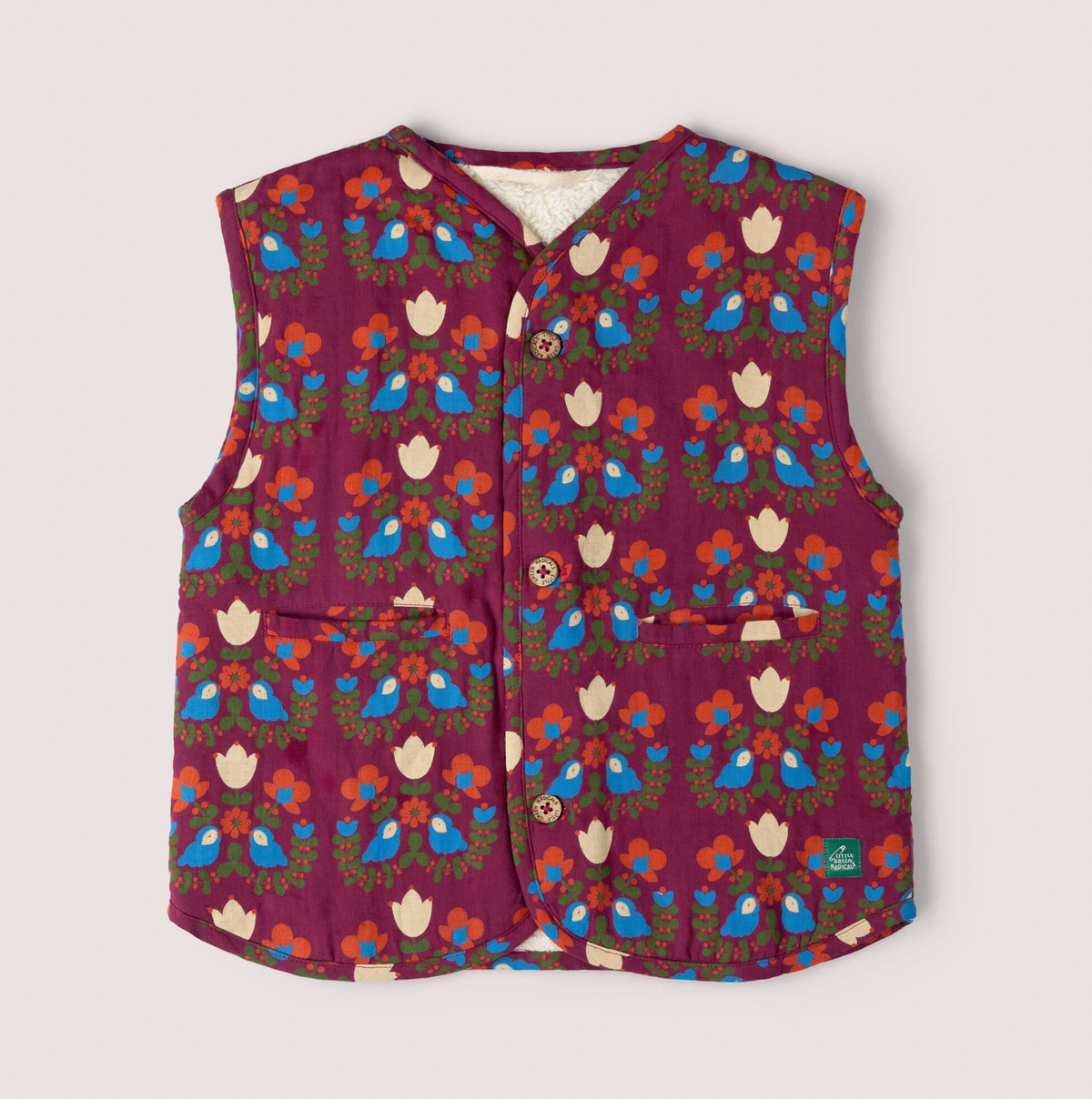 Little Green Rascals Folk Birds reversible gilet — print side front flat lay showing bold folk art repeat print of blue birds, cream tulips, orange flowers and olive green foliage on a rich burgundy base; three branded Little Green Rascals coconut shell buttons at the front, two patch pockets at the lower front, V-neckline, and natural cream sherpa lining visible at the neckline edge; Little Green Rascals green woven label at the lower right