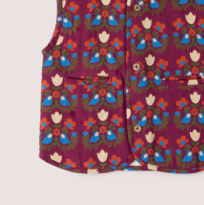 Little Green Rascals Folk Birds reversible gilet — close-up of the lower print side showing the two patch pockets with cream tulip motifs, branded coconut shell buttons and the folk art print detail of blue birds, cream tulips, orange flowers and olive green foliage on burgundy