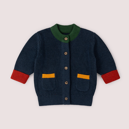 Little Green Rascals Midnight Snuggly Knitted Cardigan — front flat lay showing deep midnight navy chunky ribbed organic cotton knit, forest green ribbed round neckline, five branded Little Green Rascals coconut shell buttons down the front, two front patch pockets with mustard yellow ribbed trim, and red ribbed turned-up cuffs; ribbed hem
