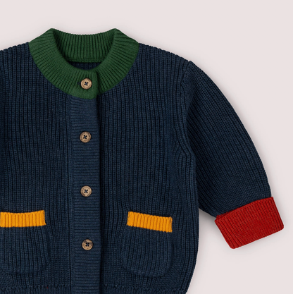 Little Green Rascals Midnight Snuggly Knitted Cardigan — close-up of the upper body and neckline showing the forest green ribbed round neckline, branded coconut shell buttons, and the deep midnight navy chunky ribbed knit texture
