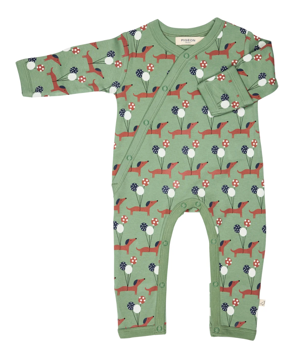 Front flat — sage green ground; terracotta dachshunds with navy ears; three-balloon bunches; kimono diagonal wrap; fold-over cuff shown; leg poppers; sage ribbed trims; Pigeon Organics label.