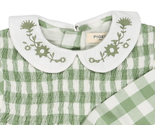 Close-up — tonal sage embroidery in sharp focus; Pigeon Organics label clearly visible; smocking construction; woven fabric texture; back neck opening.