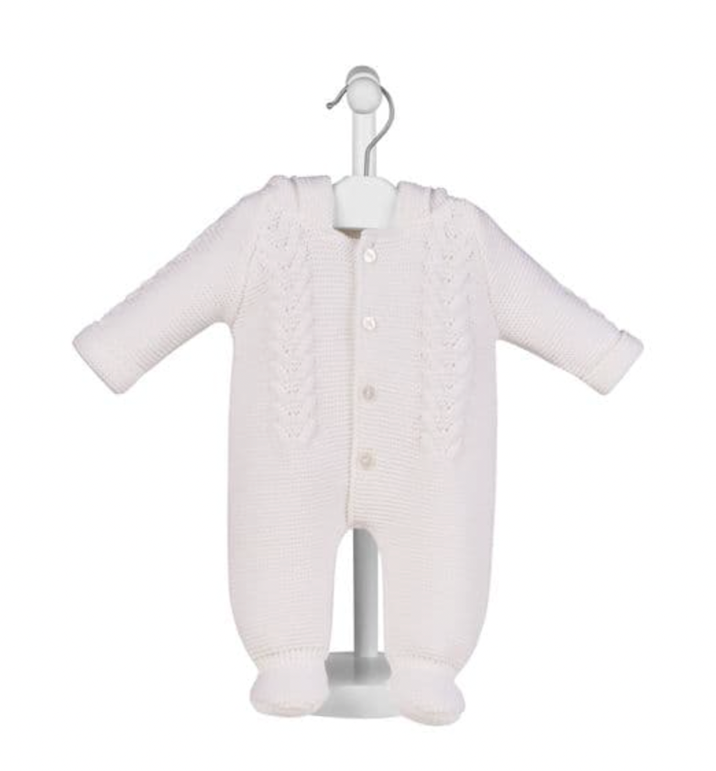 White pram suit on display stand — hood with bobble trim and ear details; cable knit front panel; 4 pearl buttons; integrated bootees; fold-over cuffs.