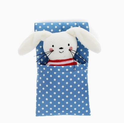  Bunny out of box in blanket; overhead flat-lay; white plush with floppy ears, pink blush cheeks, black whiskers, red and white striped top; tucked into blue polka dot pocket blanket