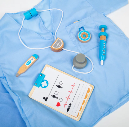 Accessories flat lay on scrubs top — stethoscope, thermometer (37°C), clipboard with ECG chart, pocket watch, syringe (1–5 markings), wooden plasters