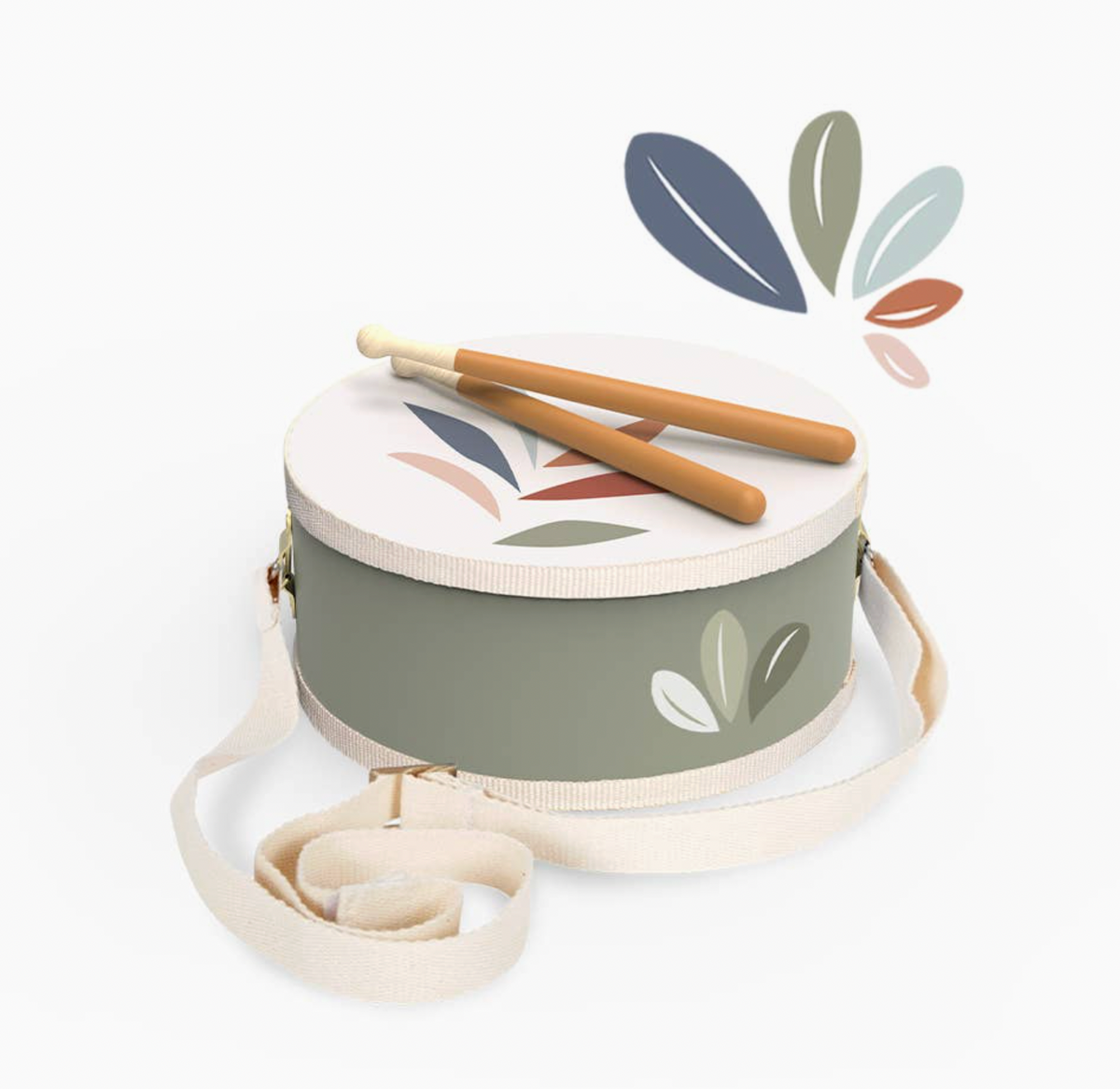 Angled overhead product shot — sage green drum, white botanical leaf head, two drumsticks crossed on top, cream strap trailing; decorative leaf graphic top right
