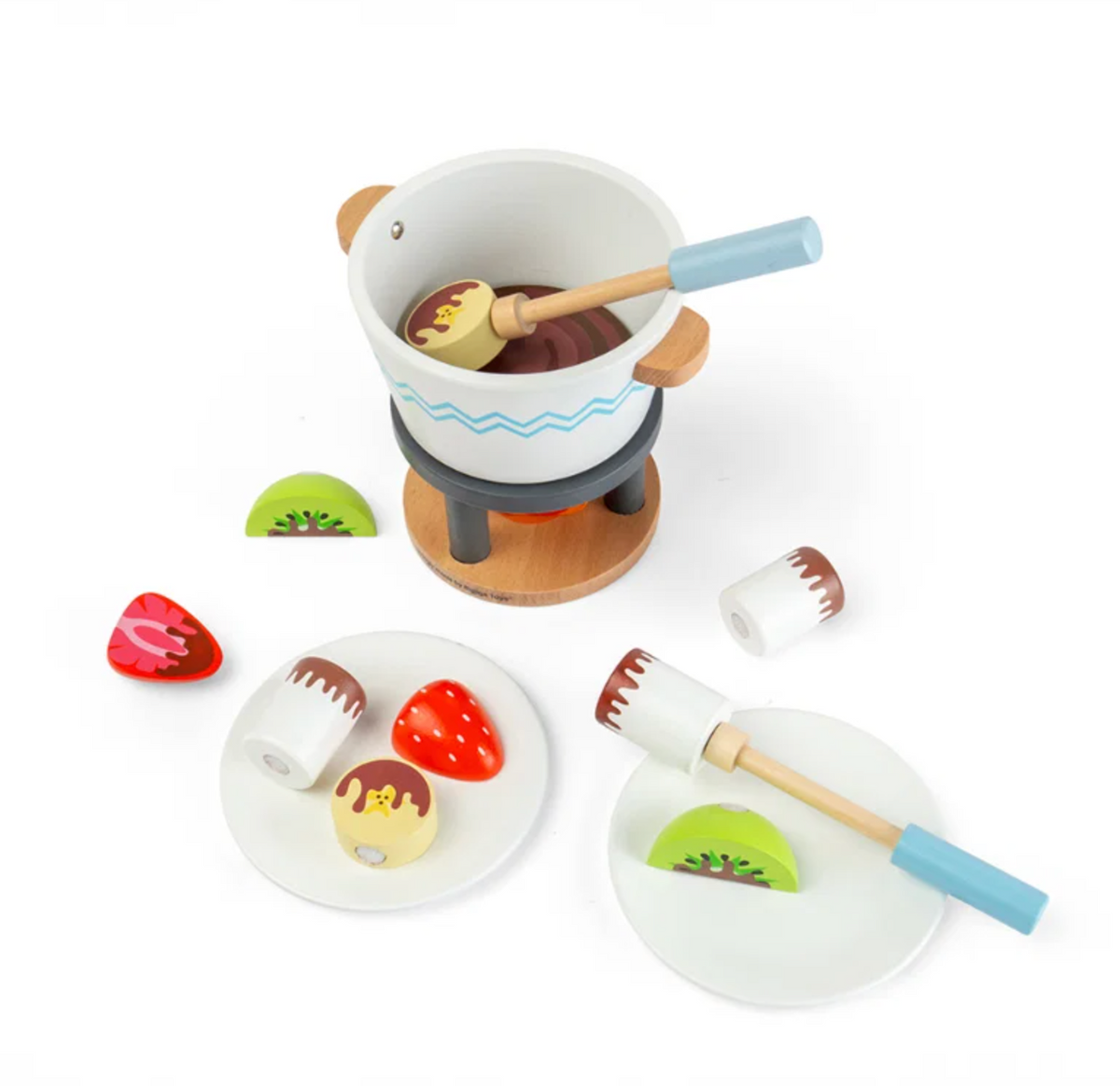 Bigjigs Toys Chocolate Pot for Two three-quarter angle view on a white background; pot and fire stand to upper left with a dipping stick inside; two white plates in the foreground showing white cylindrical marshmallows, red strawberries and pale yellow biscuits with chocolate drizzle; loose strawberry, kiwi and white marshmallow pieces scattered to the right