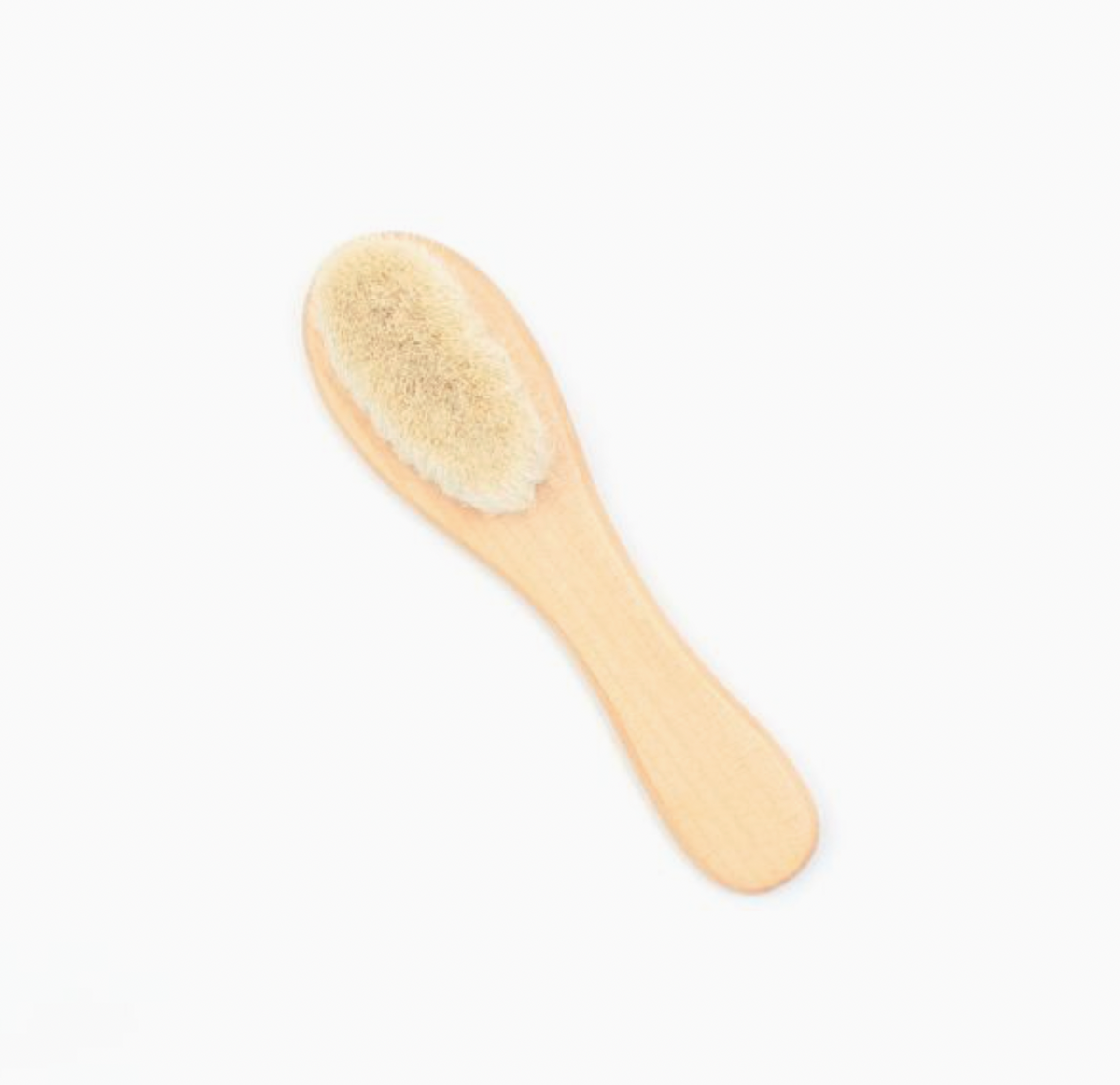 Molly and Rose Plastic Free Baby Brush shown unpackaged and laid diagonally on a plain off-white background; the full brush visible from above with the oval head filled with soft fluffy cream-coloured wool bristles at the top and the smooth warm-toned natural Grass Tree wood handle tapering to a rounded end below; the handle has a gentle waist narrowing between the brush head and the wider rounded grip