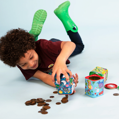 Rachel Ellen blue dinosaur money box tin shown from the side, featuring a red dinosaur, green dinosaur, colourful stripes, speech bubbles and coin slot⠋