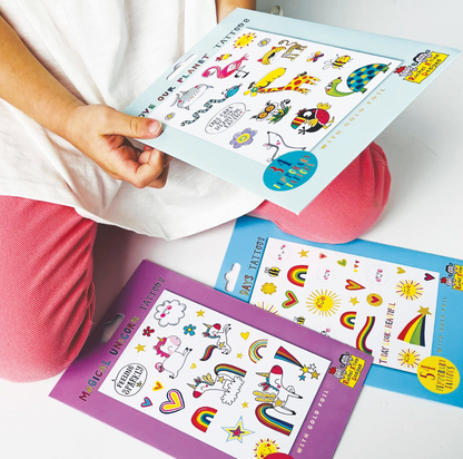 Rachel Ellen temporary tattoo packs spread out while a person holds the Love Our Planet animal design, with colourful gold foil tattoo sheets visible below