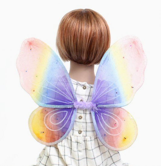Child wearing Molly & Rose pastel rainbow fairy wings over a checked dress; wings blend pink, peach, yellow, blue and lilac tones with frosty glitter and sequin stars
