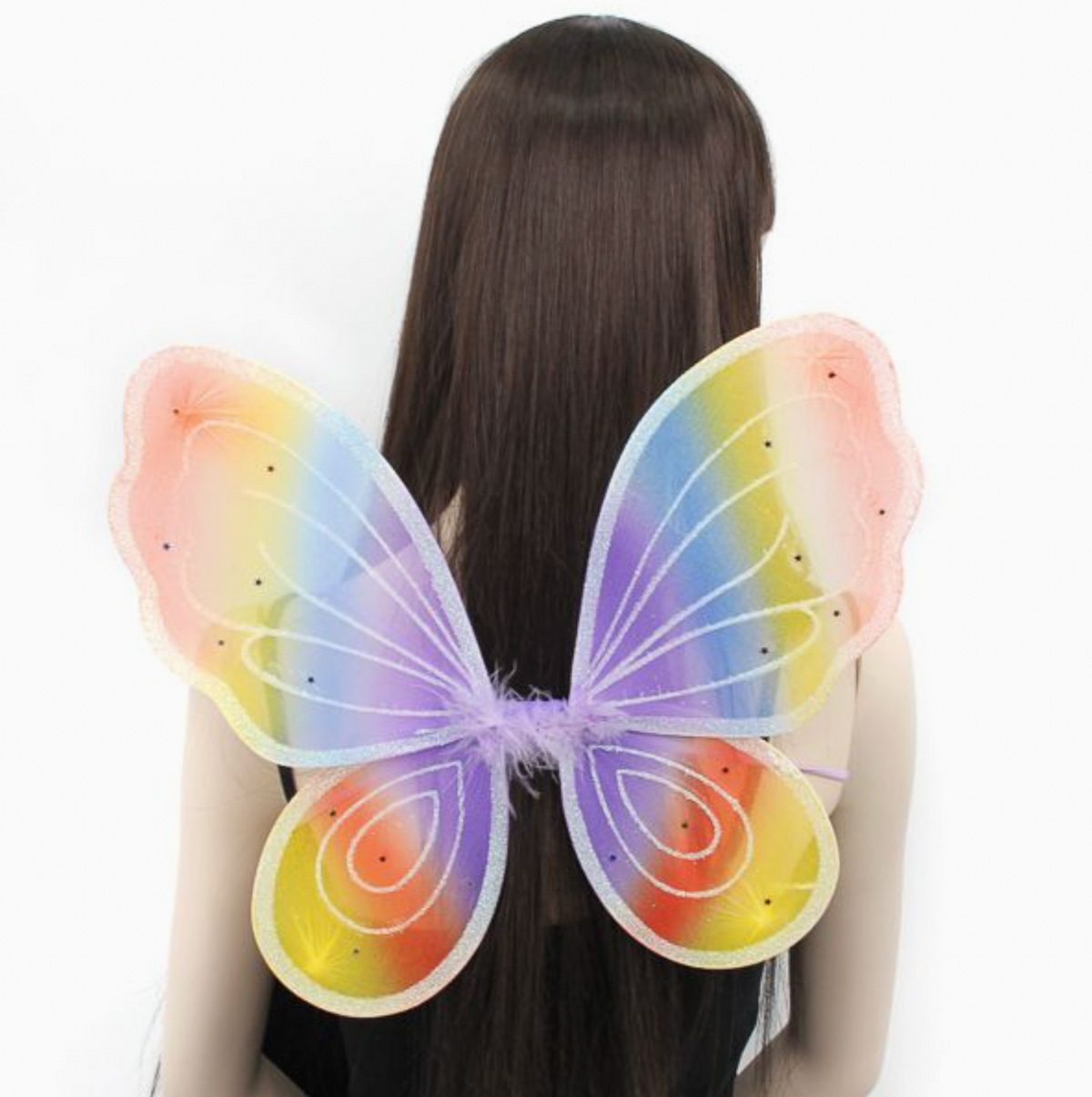 Child wearing Molly & Rose pastel rainbow fairy wings over long dark hair; lilac-edged wings feature soft rainbow colours, glitter and sequin star details
