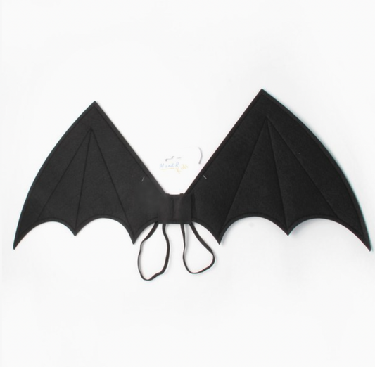 Child wearing Molly & Rose black fabric bat wings over a checked dress; pointed wing tips, scalloped lower edges, stitched panel lines and black elastic straps visible
