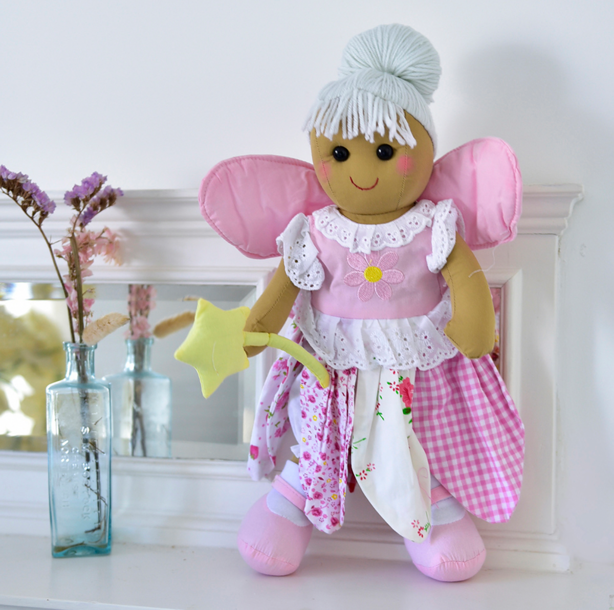 Fairy rag doll by Powell Craft wearing a pink dress with a daisy appliqué, broderie anglaise trim and a skirt of ditsy floral fabric petals.