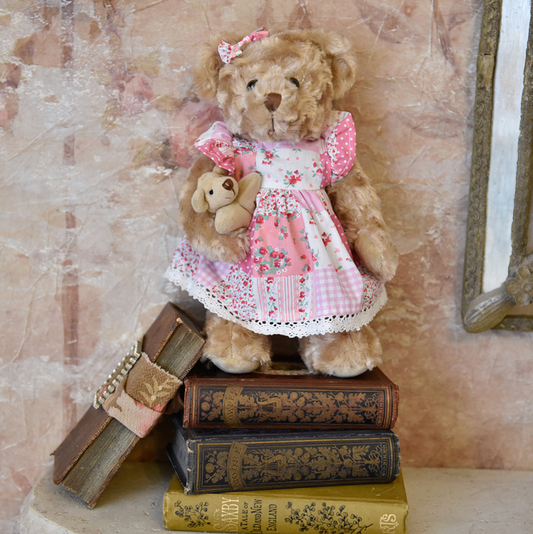 Pink patchwork dress teddy by Powell Craft, with mixed polka-dot, check, stripe and floral fabrics, crochet-lace hem and a matching ear bow.