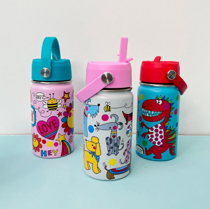 Three Rachel Ellen bottles on pale blue tabletop: turquoise Dinosaur bottle with red lid and red dinosaur at right, white Dogs bottle with raised pink straw in front, and pale pink bottle with turquoise lid behind left showing bee, flowers, rainbow heart and BUZZ, LOVE and HEY lettering.