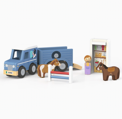 Jumini blue wooden jeep and open horse trailer on white background, with black wheels, grey hubs, printed dog in jeep window and JUMINI front plate; chestnut-and-white horse beside red-and-blue jump fence, peg person in purple dungarees, brown saddled horse and detached white roof upright as illustrated tack storage.