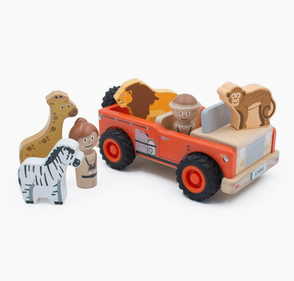 Jumini Safari Jeep set arranged on white: orange jeep with natural-wood bonnet, black treaded wheels and JUMINI front plate at right, lion in rear, monkey on bonnet and safari figure seated; spotted giraffe, striped zebra and second beige-clad figure stand at left.