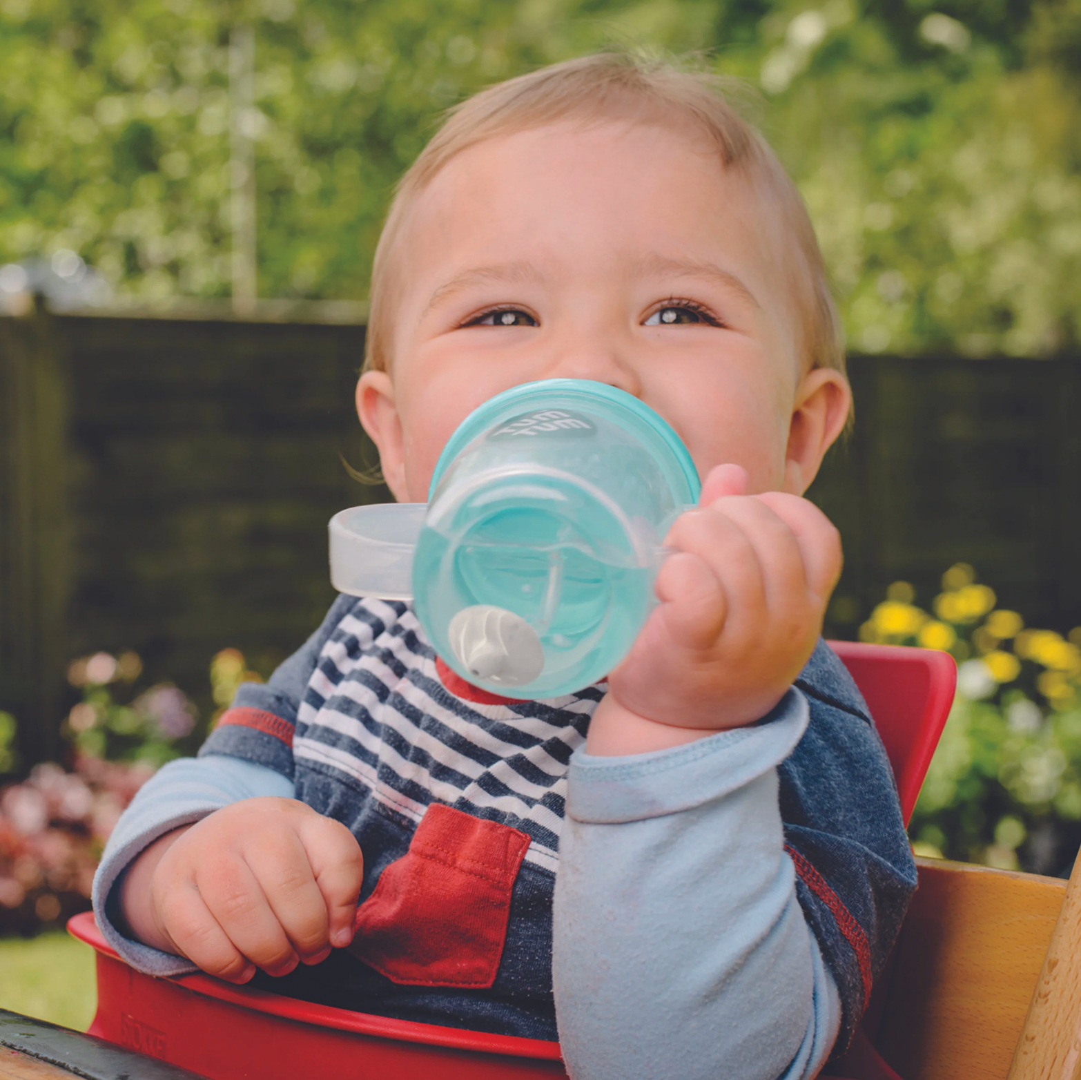 Child drinking from a blue sippy cup outdoors. TIPPY CUP WITH STRAW AND FLIP TOP LEAKPROOF LID - BORIS BEAR BLUE | TUM TUM