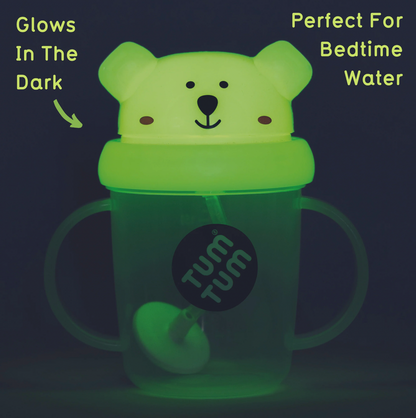 Glowing green cup with bear design and 'Tum Tum' branding on a dark background. TIPPY CUP WITH STRAW AND FLIP TOP LEAKPROOF LID - PETE POLAR BEAR (GLOW IN THE DARK)  | TUM TUM