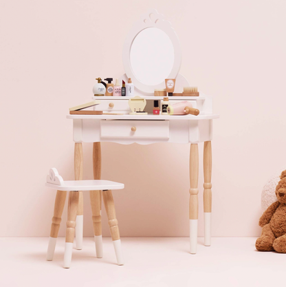 Small vanity table with mirror and stool against a light pink wall, teddy bear on the side. VANITY STAR BEAUTY KIT & WOODEN ACCESSORIES | LE TOY VAN