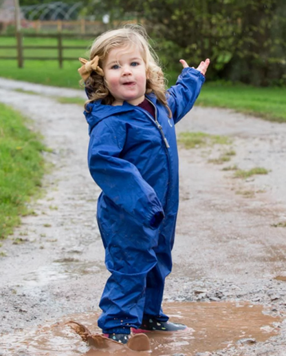 Child in a blue rain suit standing on a muddy path outdoors. WATERPROOF TODDLER ALL-IN-ONE PACKASUITS - BLUE | HIPPYCHICK 