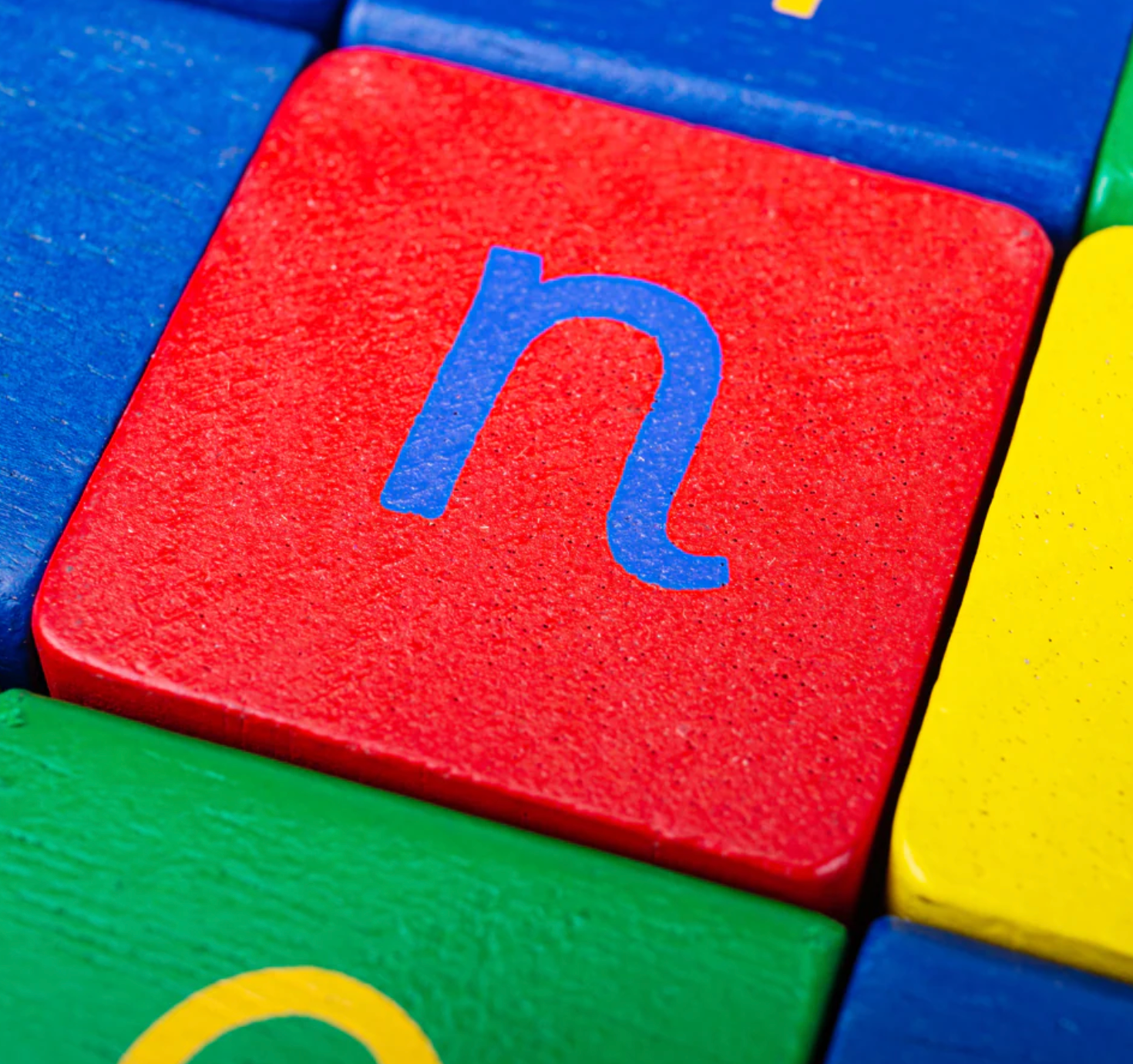 Colorful blocks with letters, focusing on a red block with a blue 'n'. WOODEN BABY MULTI-COLOUR WALKER WITH ABC & NUMBER BLOCKS | TIDLO