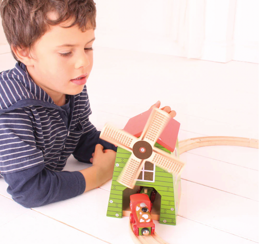 Child playing with a wooden windmill toy. WOODEN COUNTRY WINDMILL TRAIN SET ACCESSROY | BIGJIGS