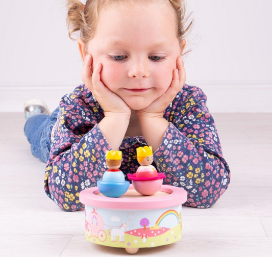 Child playing with a colorful toy music box on a light surface. WOODEN FANTASY MUSIC BOX | BIGJIGS