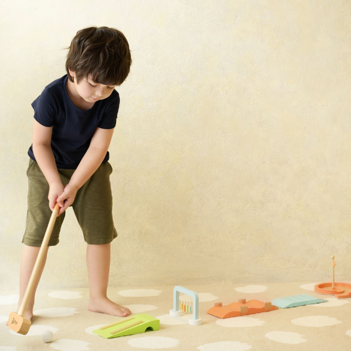 Child playing with wooden toys on a light-colored floor. WOODEN GOLF SET | CLASSIC WORLD