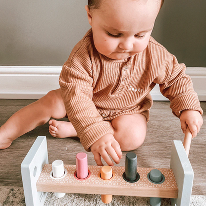Child playing with a wooden toy on a wooden floor. WOODEN HAMMER BENCH | BIGJIGS