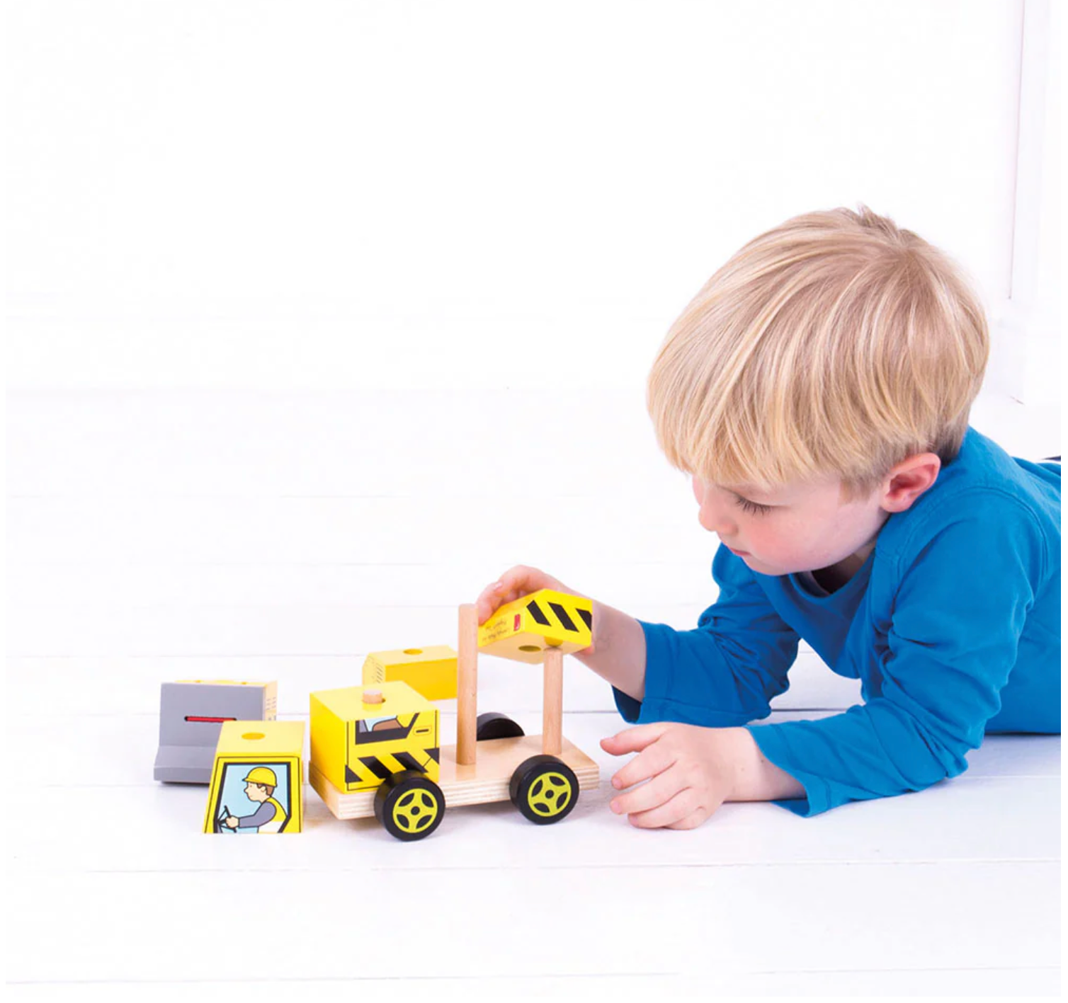 Child playing with a wooden toy construction set on a white surface WOODEN STACKING BULLDOZER | BIGJIGS