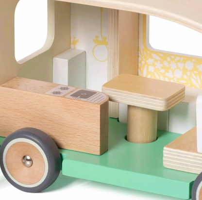 Close-up of a wooden toy vehicle with a green base and beige and gray details. WOODEN TOY CAMPER VAN PLAYSET | CLASSIC WORLD