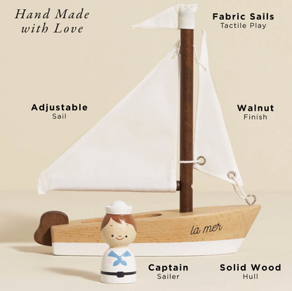 Wooden sailboat with fabric sails and a small figurine of a sailor on a beige background. WOODEN TOY SAILING BOAT & CAPTAIN | LE TOY VAN