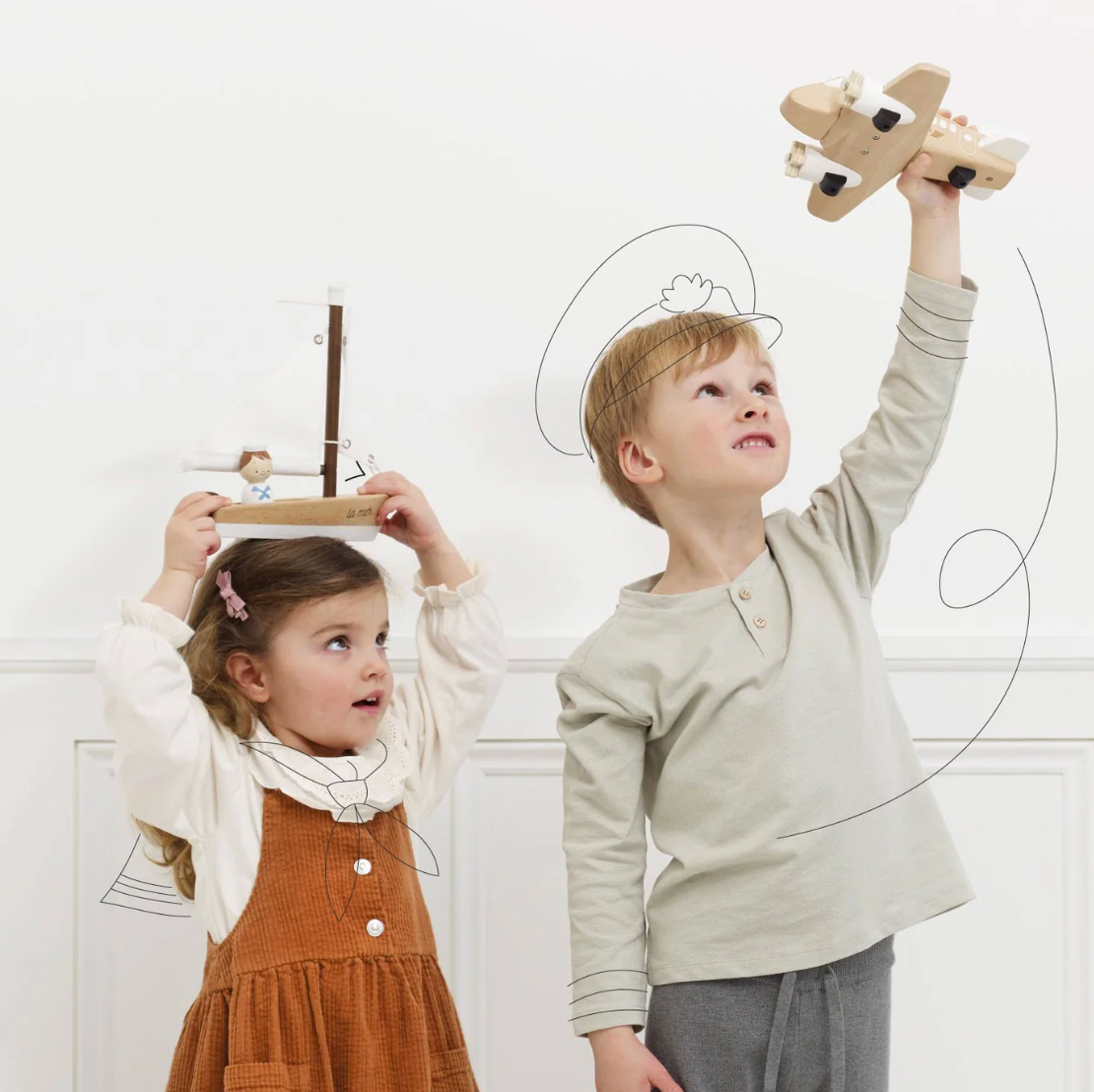 Two children playing with wooden toys against a white wall. WOODEN TOY SAILING BOAT & CAPTAIN | LE TOY VAN