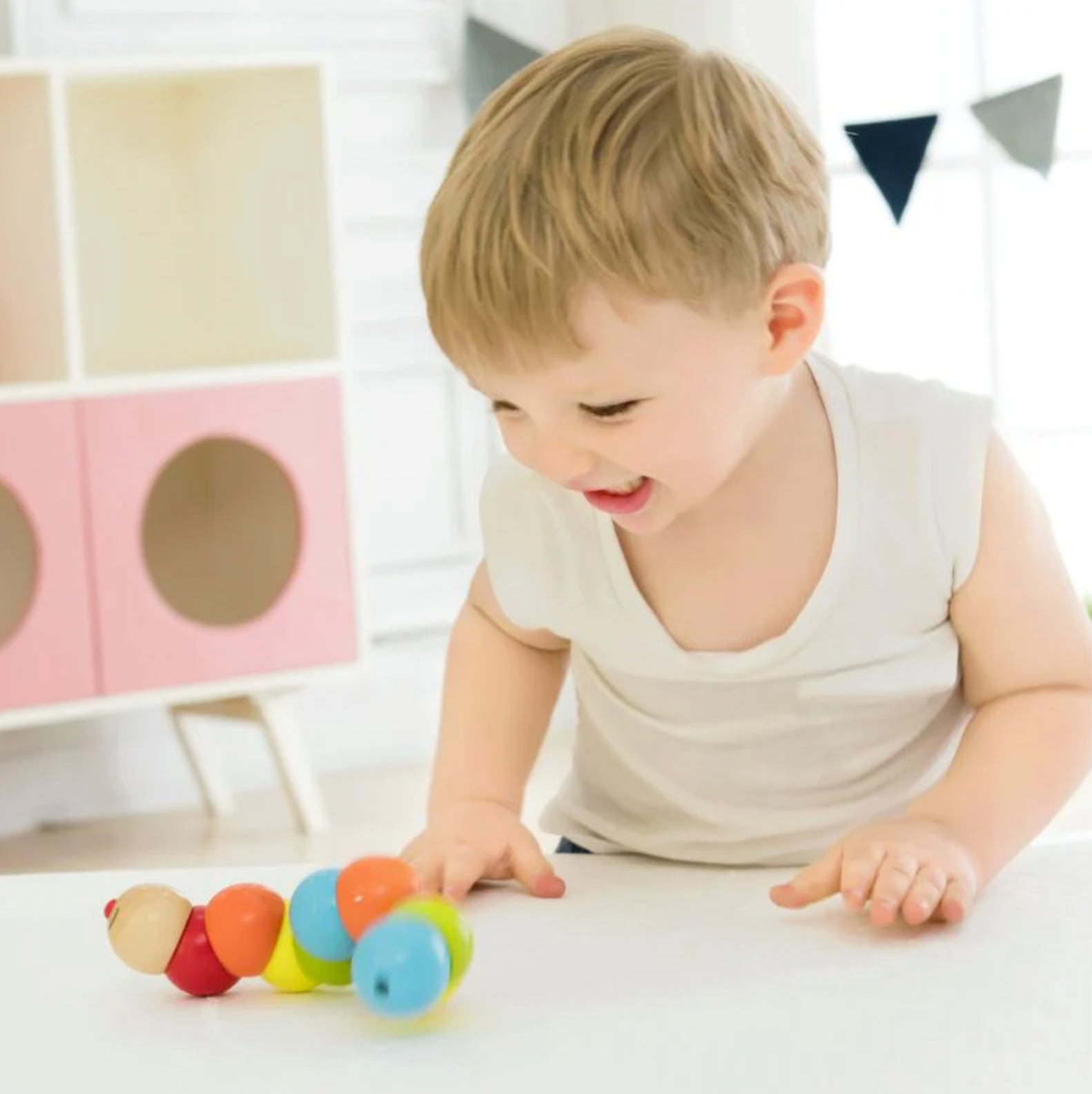 Child playing with a colorful toy in a bright room. WOODEN TWISTY CATERPILLAR | CLASSIC WORLD