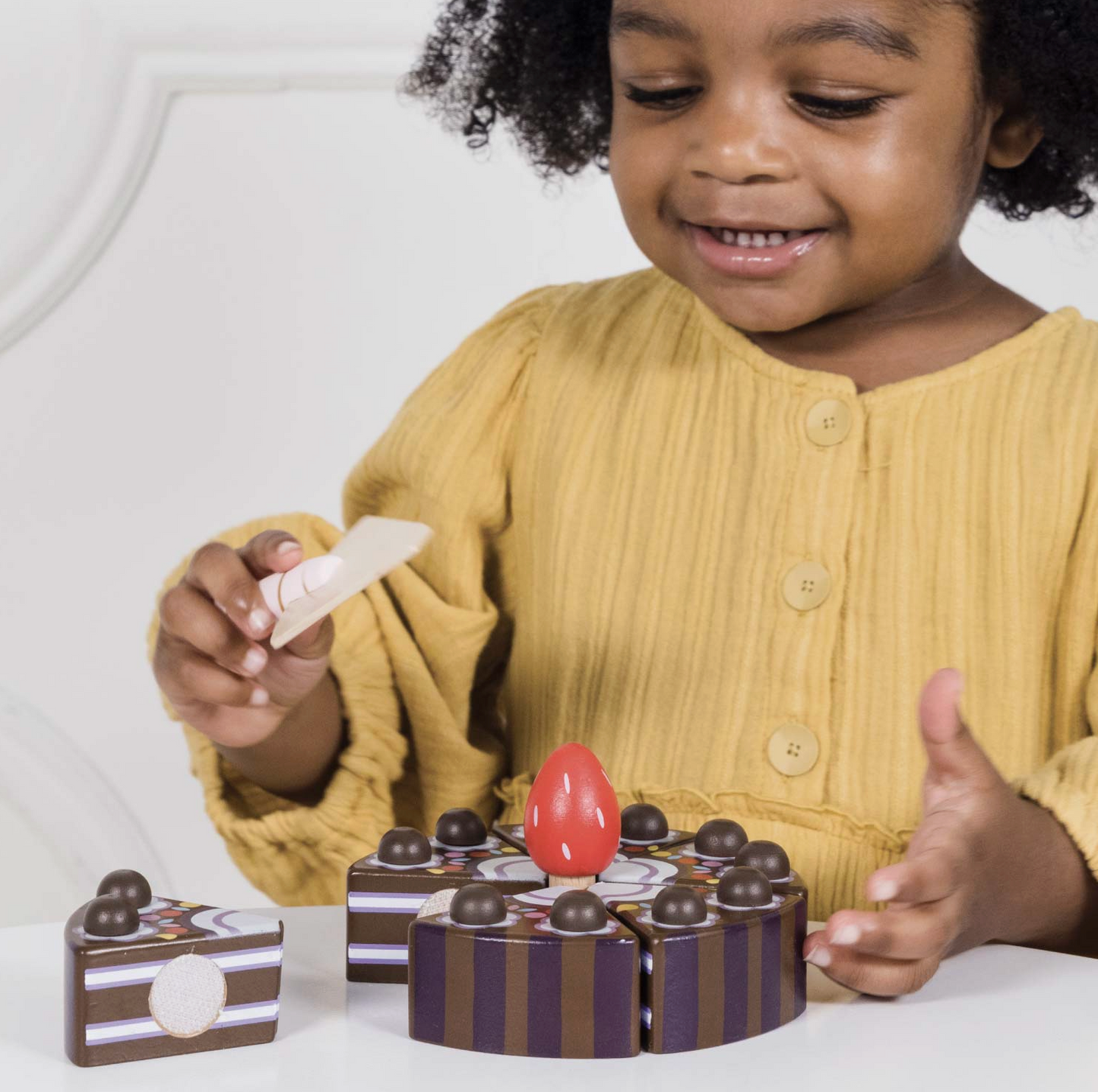 The Le Toy Van chocolate gateau toy cake styled beautifully as a high-quality educational gift for a children's playroom.