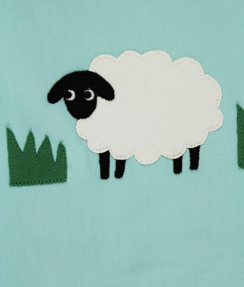 Close-up detail of the fabric sheep and grass appliqué stitching on the Toby Tiger organic cotton kids top.